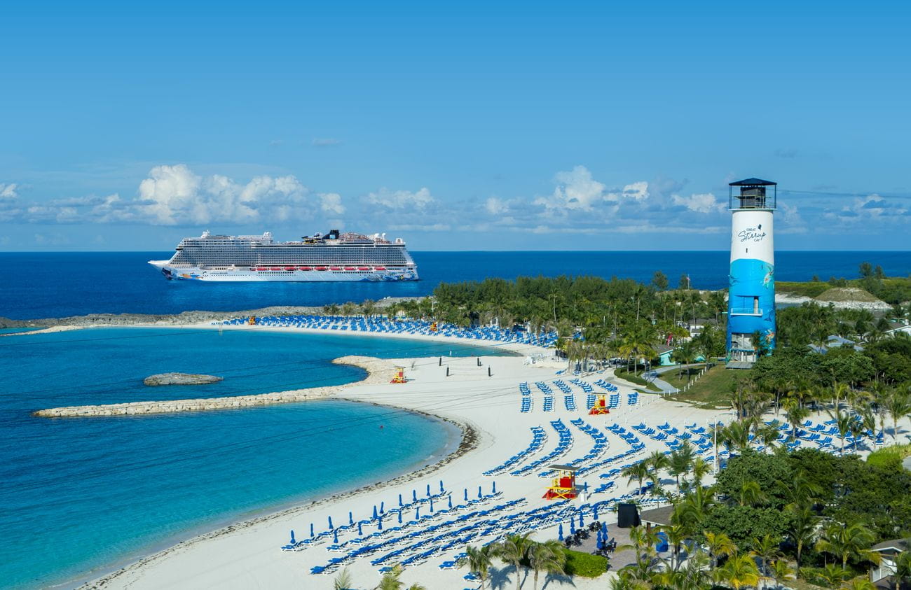 Norwegian Escape anchored off Great Stirrup Cay with white sand beach, turquoise lagoon, and lighthouse