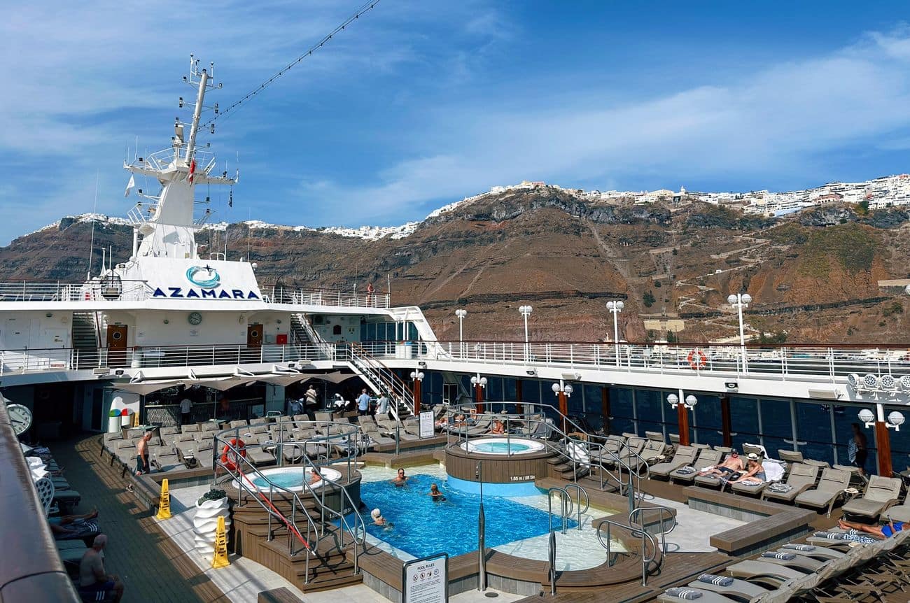 Pool deck with swimming pool and Santorini cliffs beyond