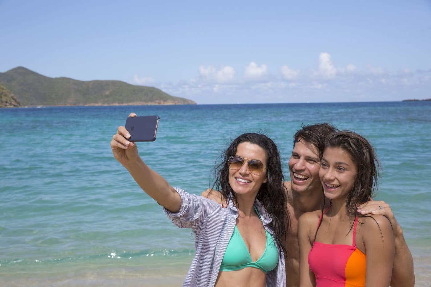 Friends taking a beach selfie by turquoise water