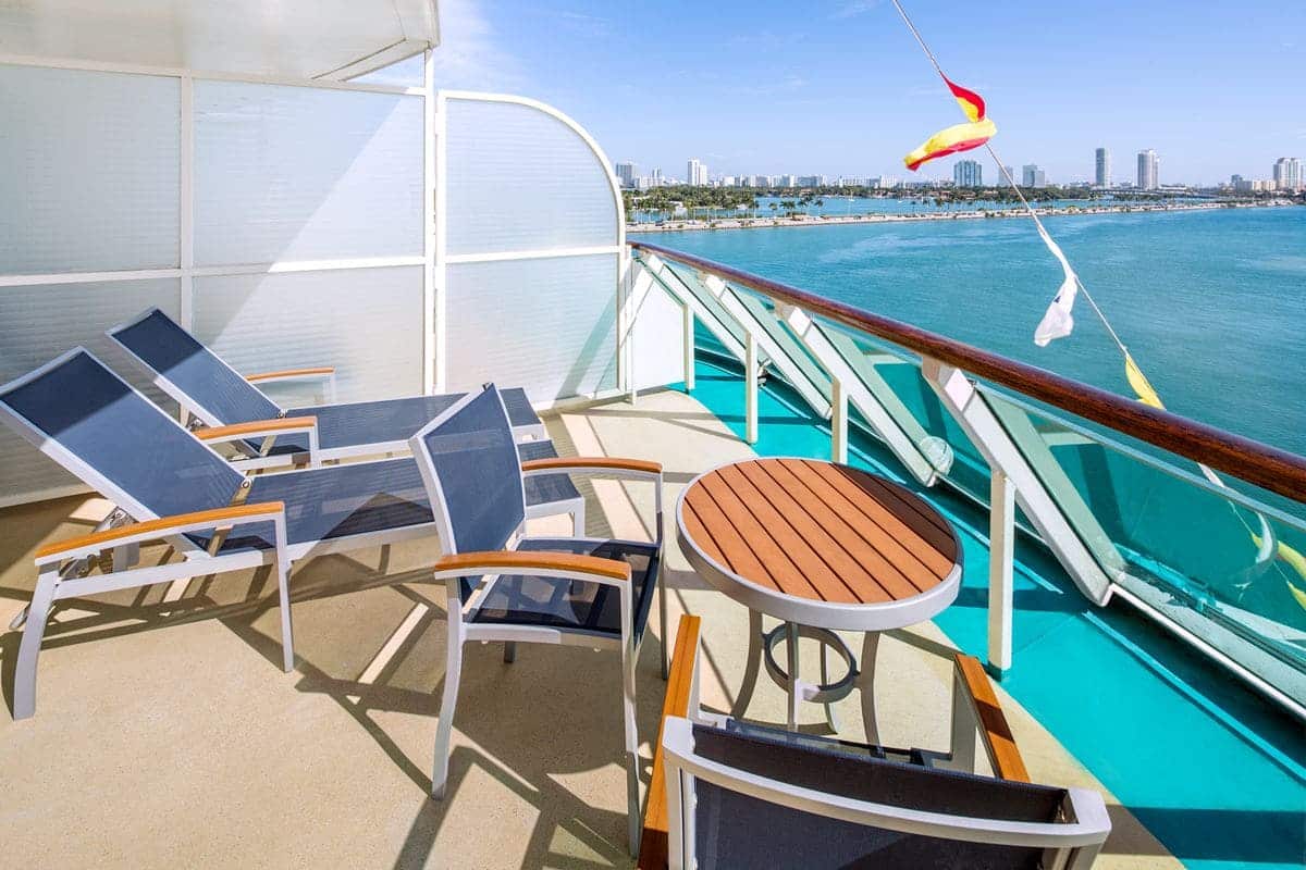 Aft balcony of a Junior Suite on Enchantment of the Seas with lounge chairs and ocean view