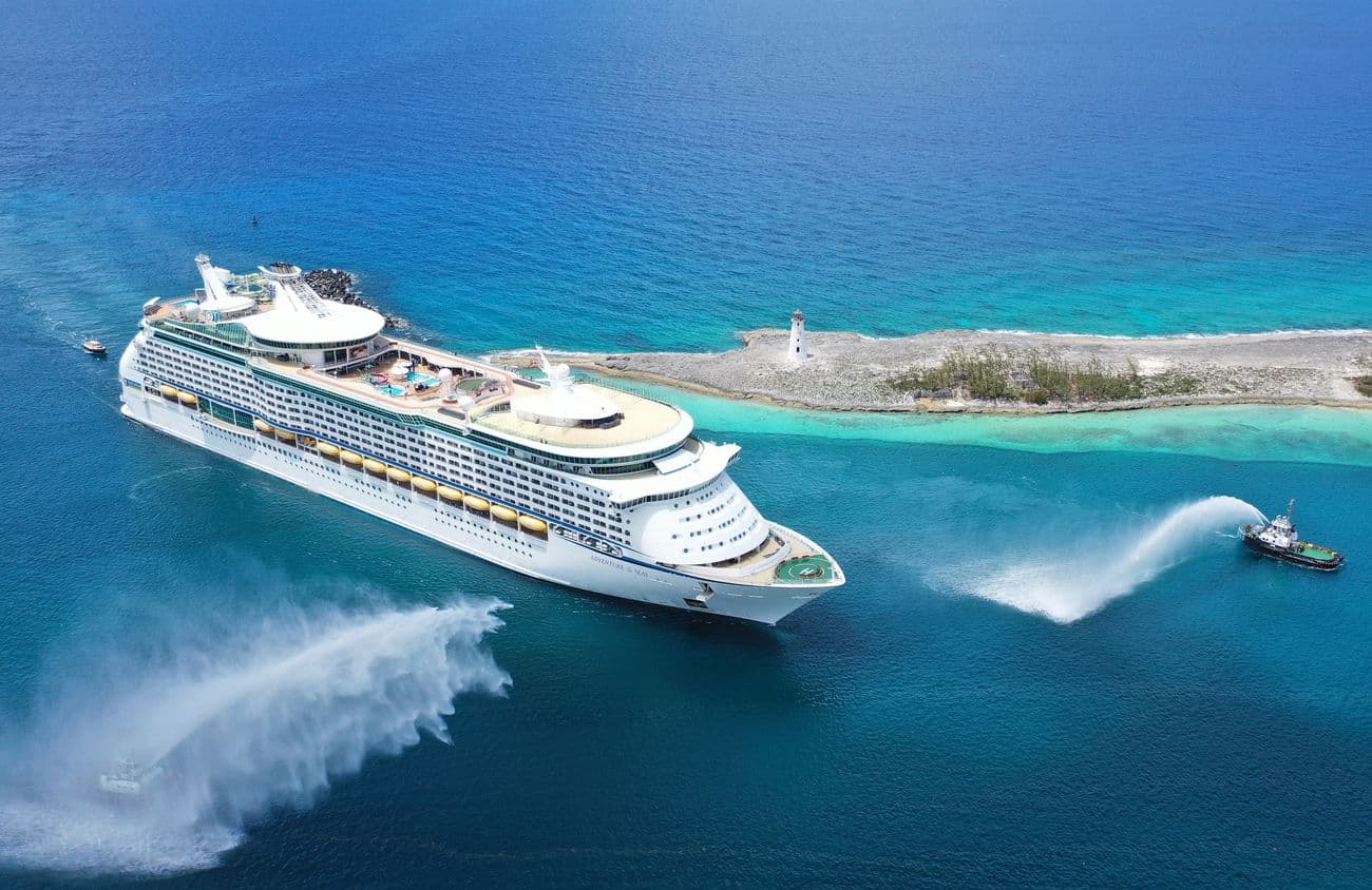 Adventure of the Seas arriving at Nassau with tugboats spraying water beside the island