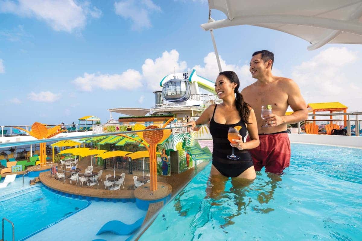 Couple enjoying drinks in a hot tub overlooking the pool deck