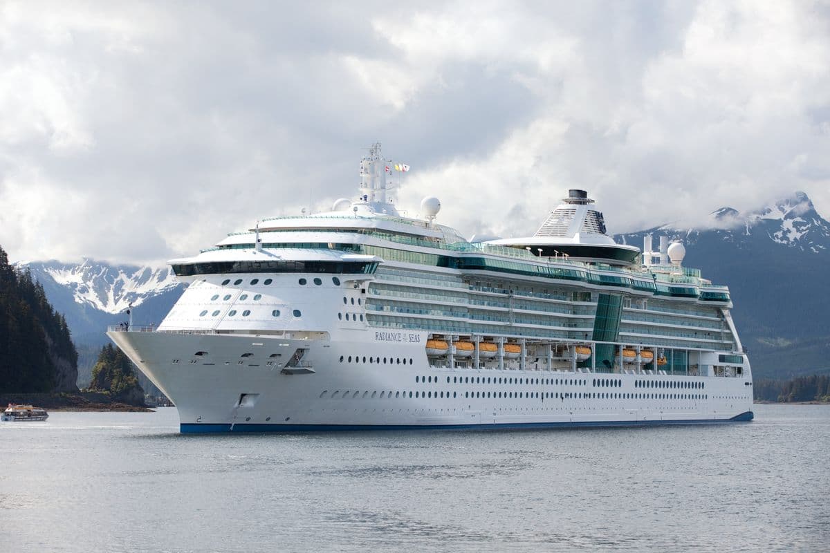 Royal Caribbean’s Radiance of the Seas cruising through Alaska with snow-capped mountains in the background