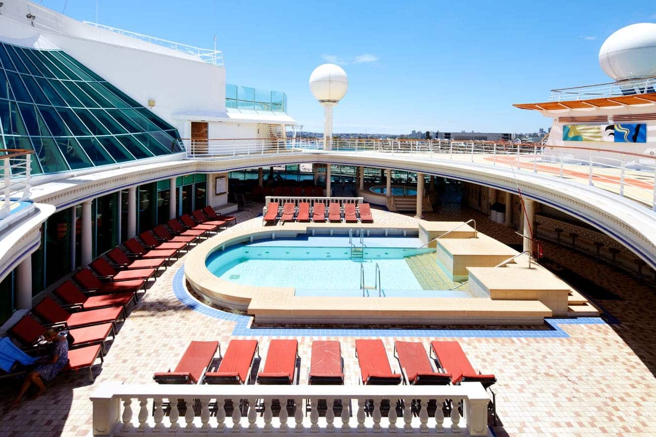 Solarium pool area with red loungers and glass roof