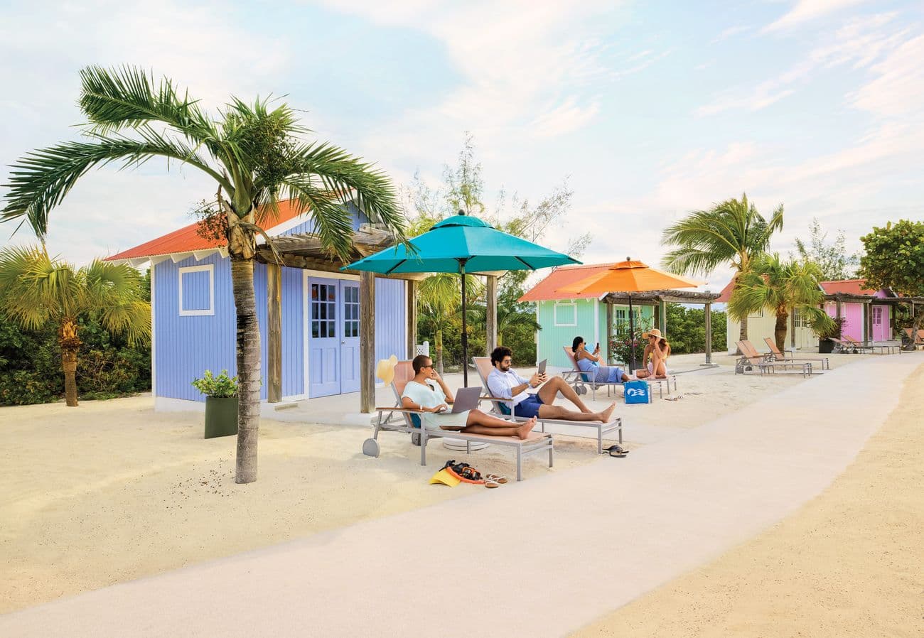 Guests resting outside colorful Princess Cays bungalows