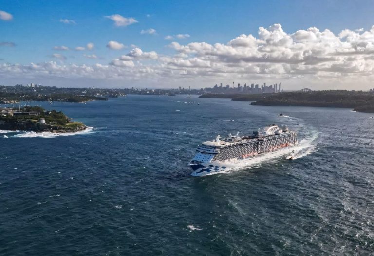 Royal Princess sailing into Sydney Harbour with the city skyline and rugged headlands in the background under bright scattered clouds - 2027–28 Australia Summer Deployment