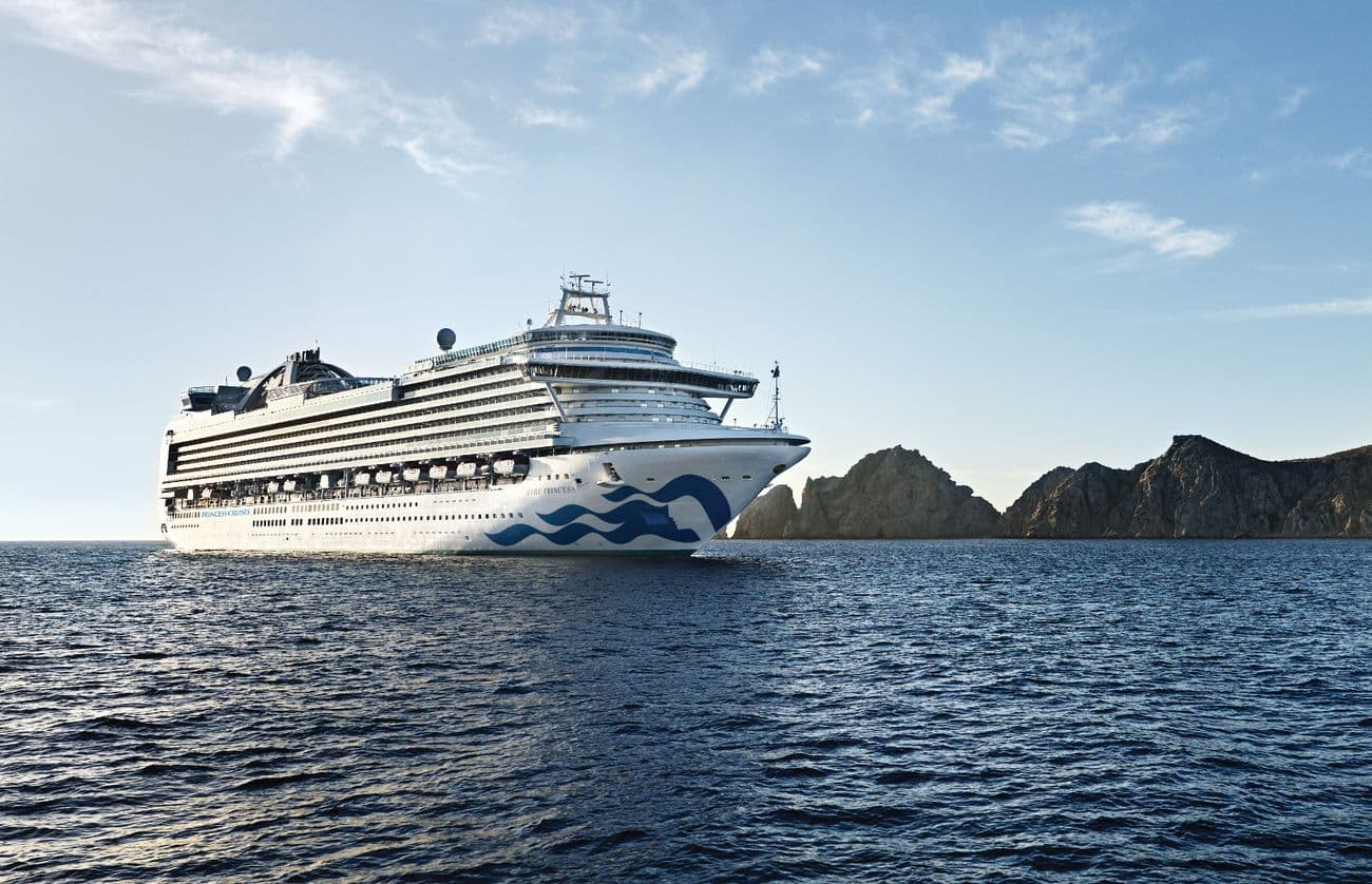 Ruby Princess cruising along the Mexican Riviera with rocky coastline in the background