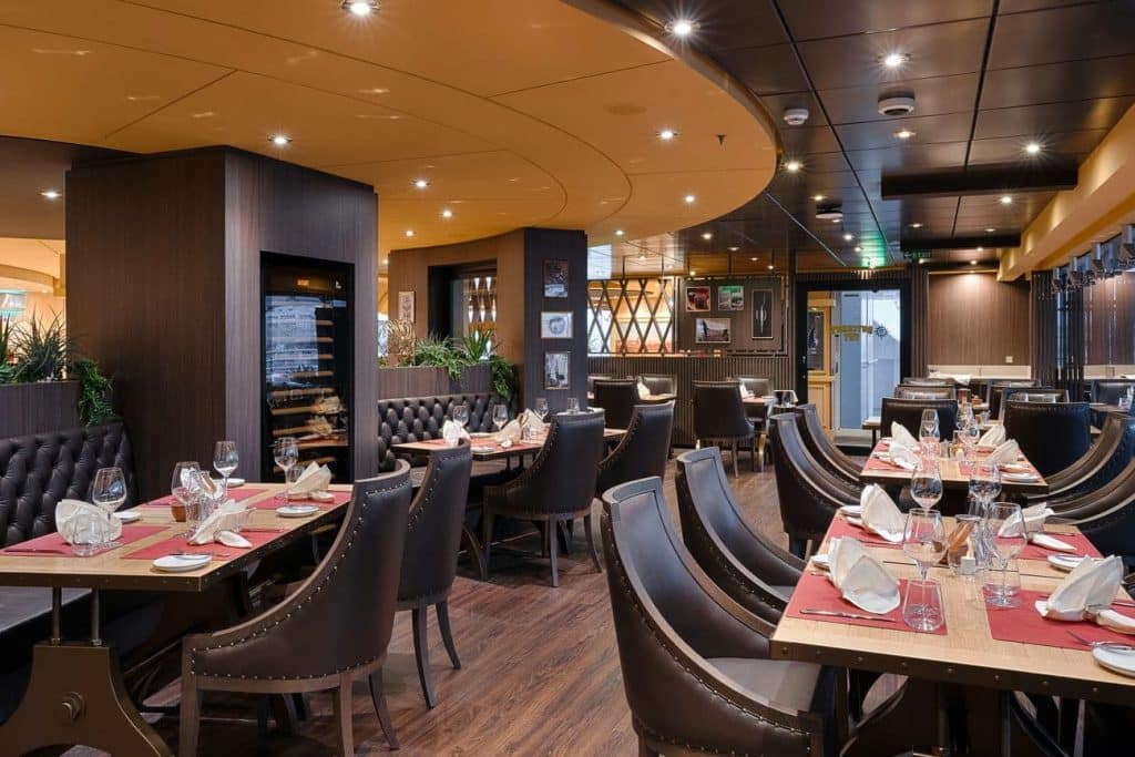 Butcher’s Cut steakhouse restaurant aboard MSC Magnifica with elegantly set tables and leather seating