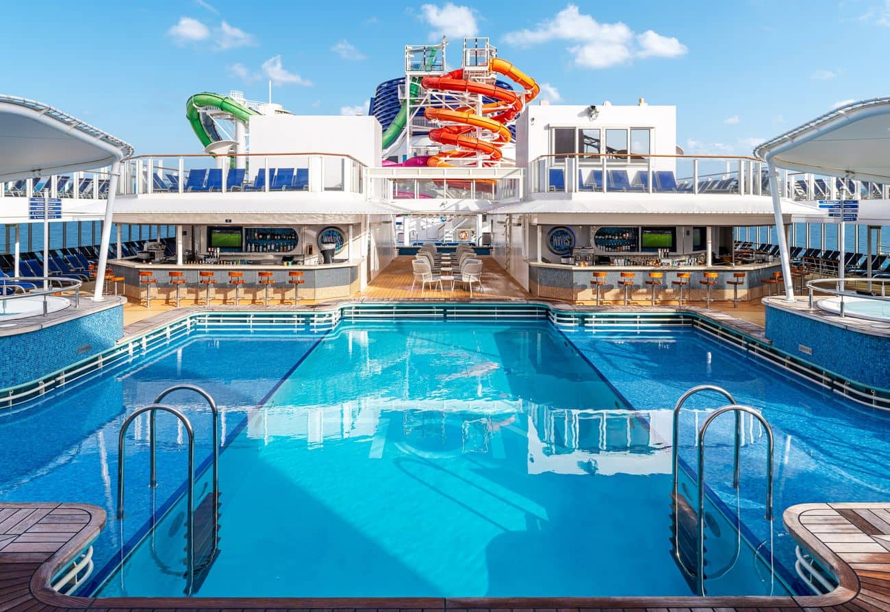 Main pool deck with waterslides, sun loungers, and poolside bars