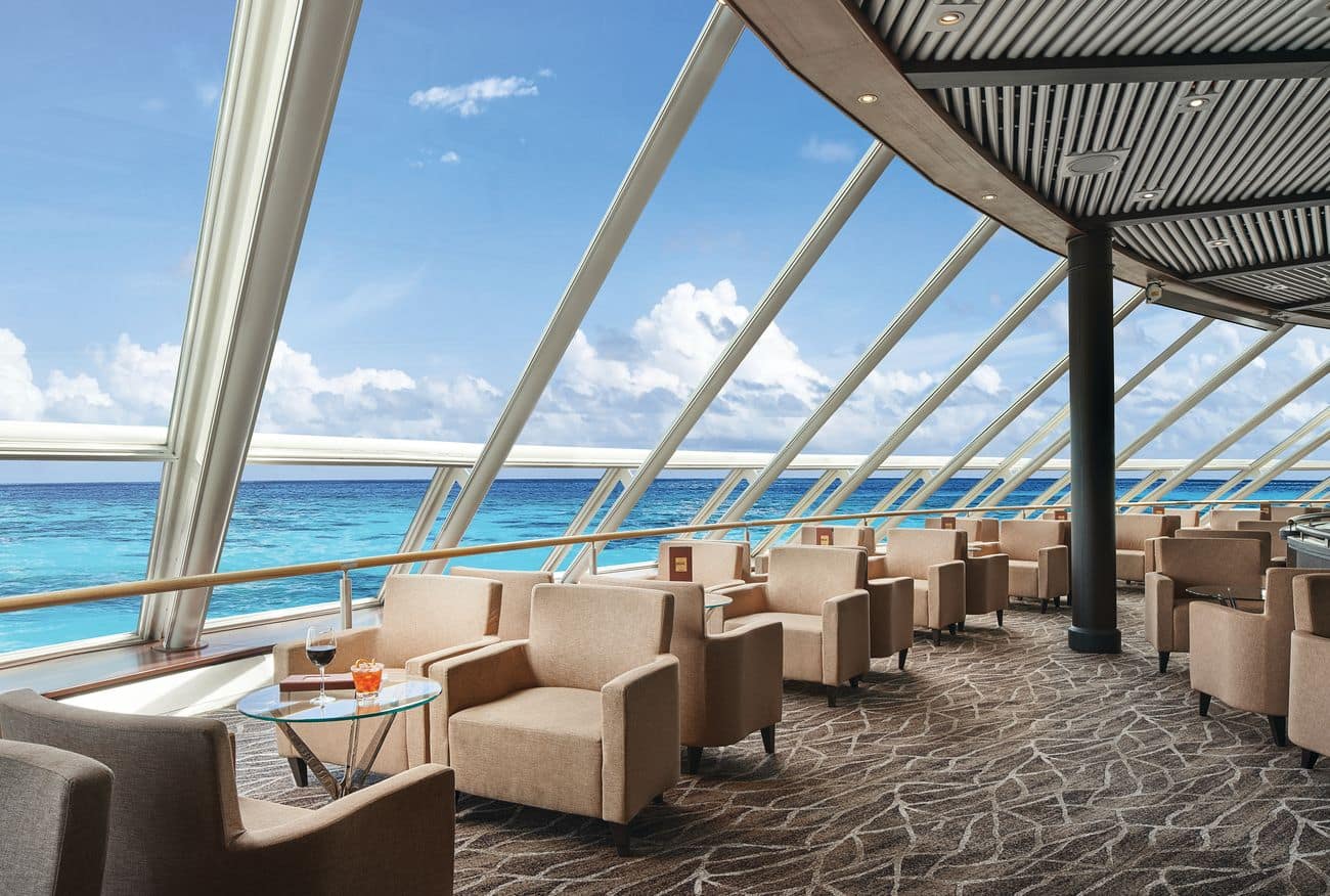 Spinnaker Lounge aboard Norwegian Sky with panoramic windows, lounge chairs, and ocean views