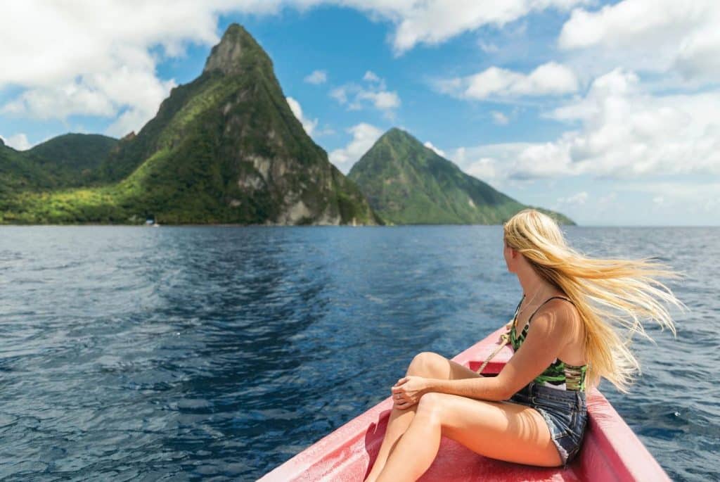 Woman seated at the bow of a small boat heading toward the Pitons in St. Lucia on a bright sunny day