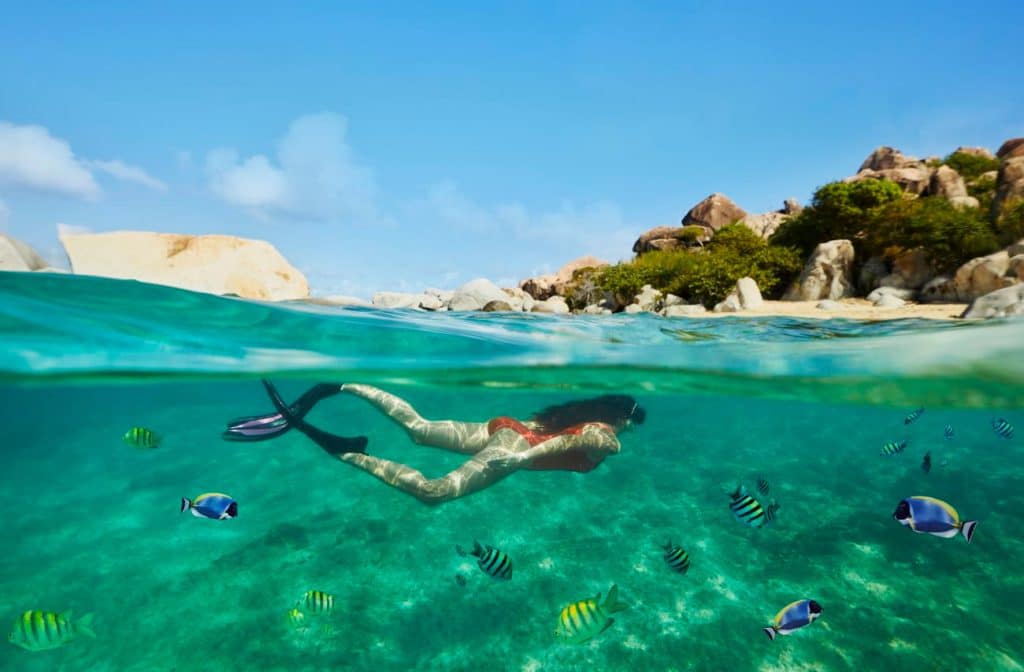 Snorkeler swimming above coral reefs near Virgin Gorda with tropical fish in clear turquoise water