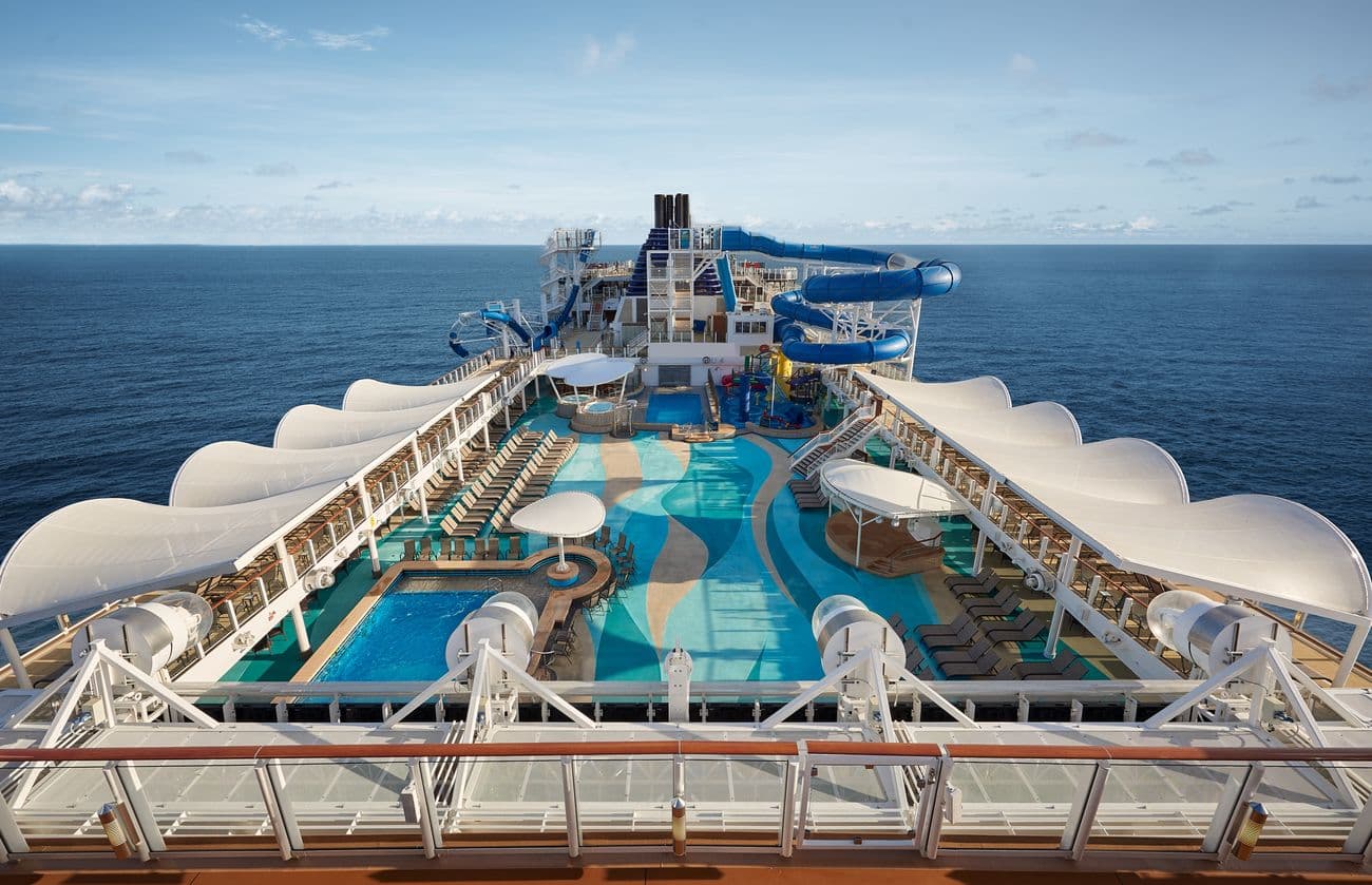 Norwegian Joy top deck with main pool, waterslides, sun loungers, and ocean views