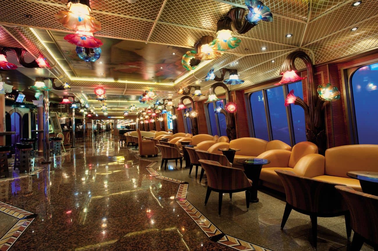 Carnival Conquest interior promenade with decorative glass ceiling lights, polished floors, and rows of comfortable lounge seating