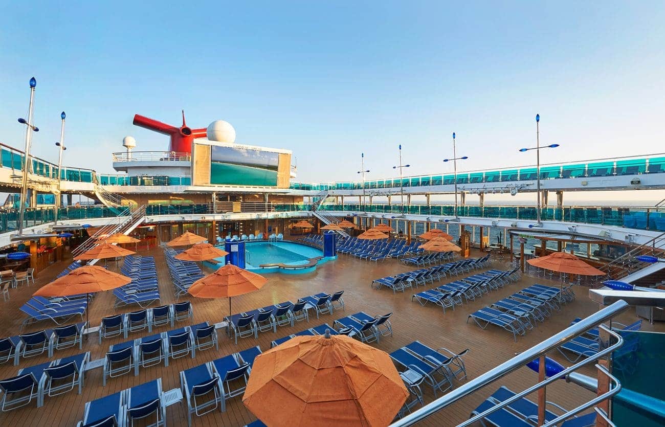 Resort-style main pool deck with loungers and giant outdoor screen