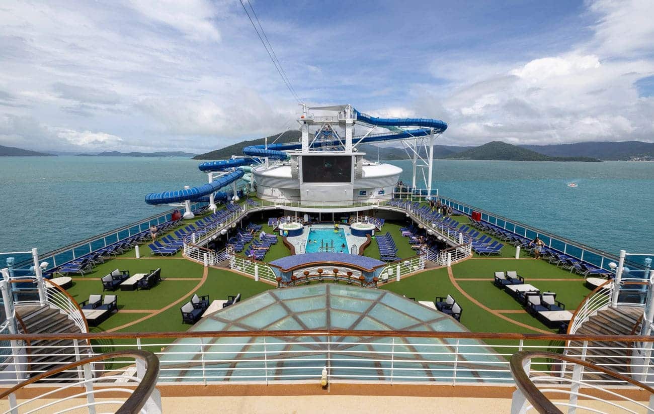 Carnival Encounter sun deck with pool and water slides overlooking ocean