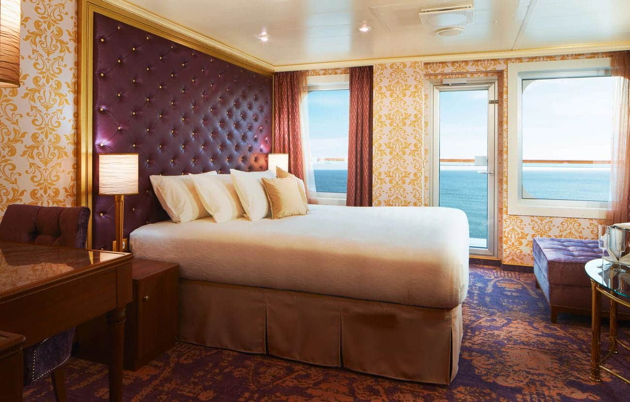 Elegant cruise suite bedroom with balcony ocean view and decorative Italian-style furnishings