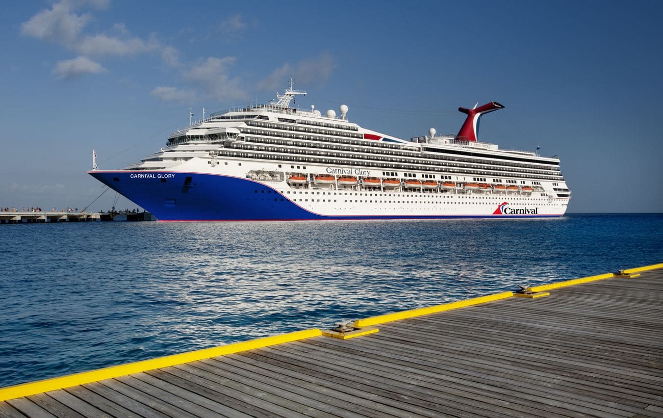 Carnival Glory cruise ship docked beside Caribbean pier with distinctive blue hull and white superstructure