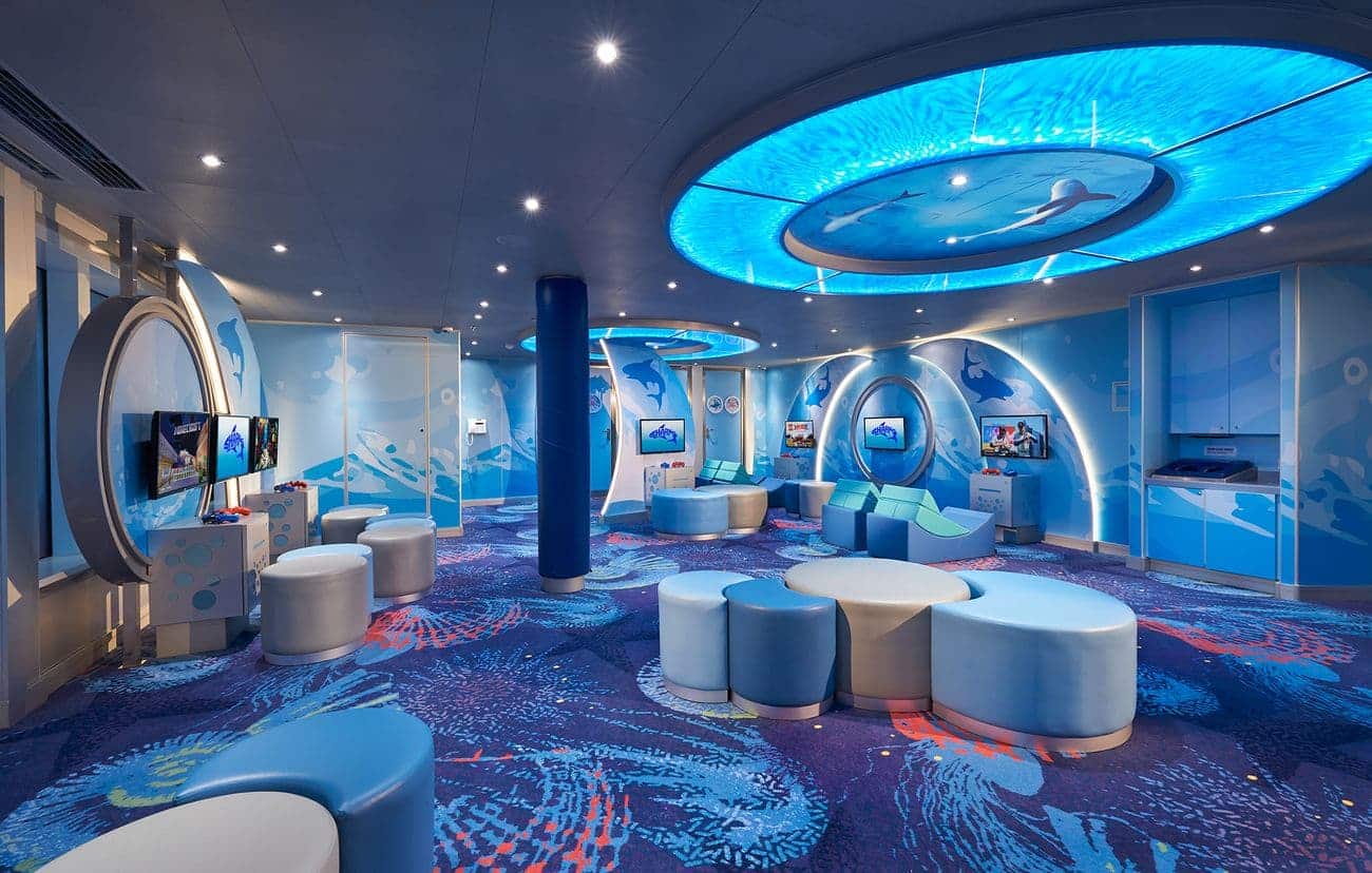 Kids play area with ocean-themed decor, interactive screens, and soft seating in Camp Ocean Sharks onboard