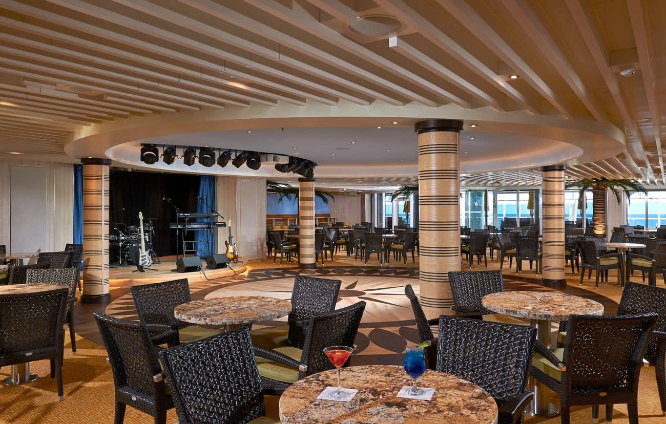 Carnival Horizon Ocean Plaza lounge with live music stage, round tables, and open seating near large windows