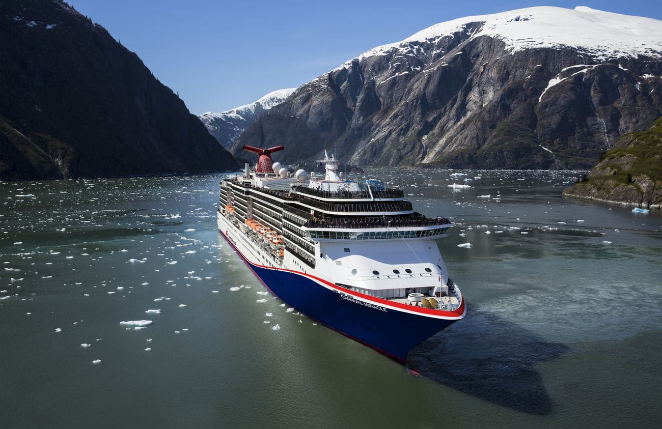 Carnival Miracle sailing through icy Alaskan fjord with glaciers and mountains