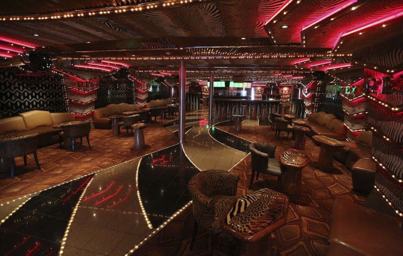 Neon-lit dance club lounge with patterned seating and glossy dance floor