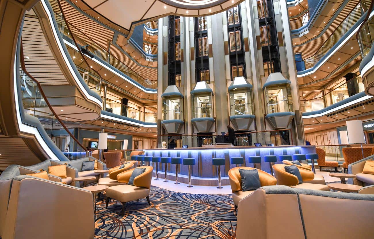 Multi-deck atrium lounge with glass elevators and central bar