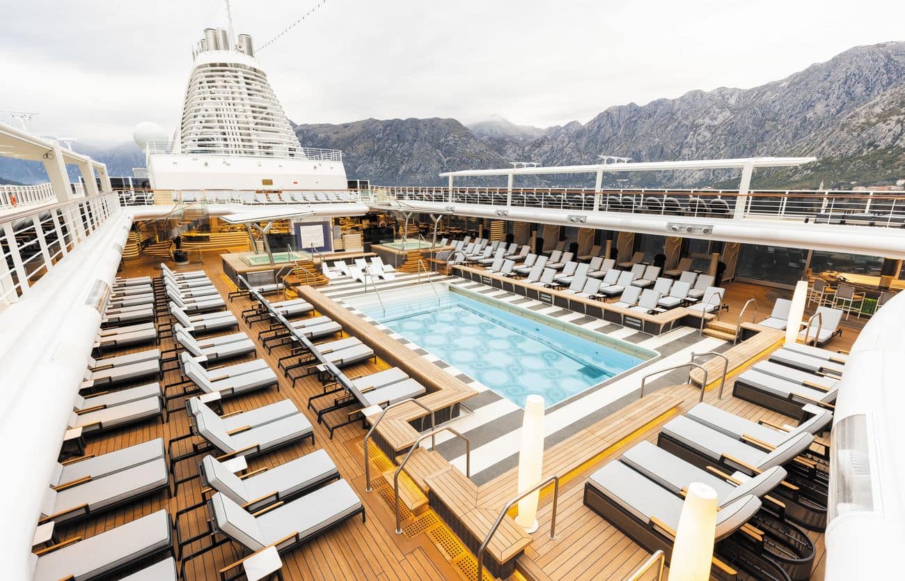 Resort-style pool deck with loungers and central pool on a luxury cruise ship