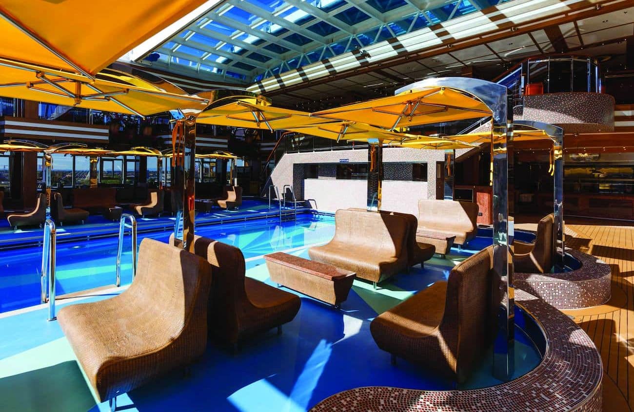 Indoor Lido Diana pool area with loungers, yellow umbrellas, and a glass roof.