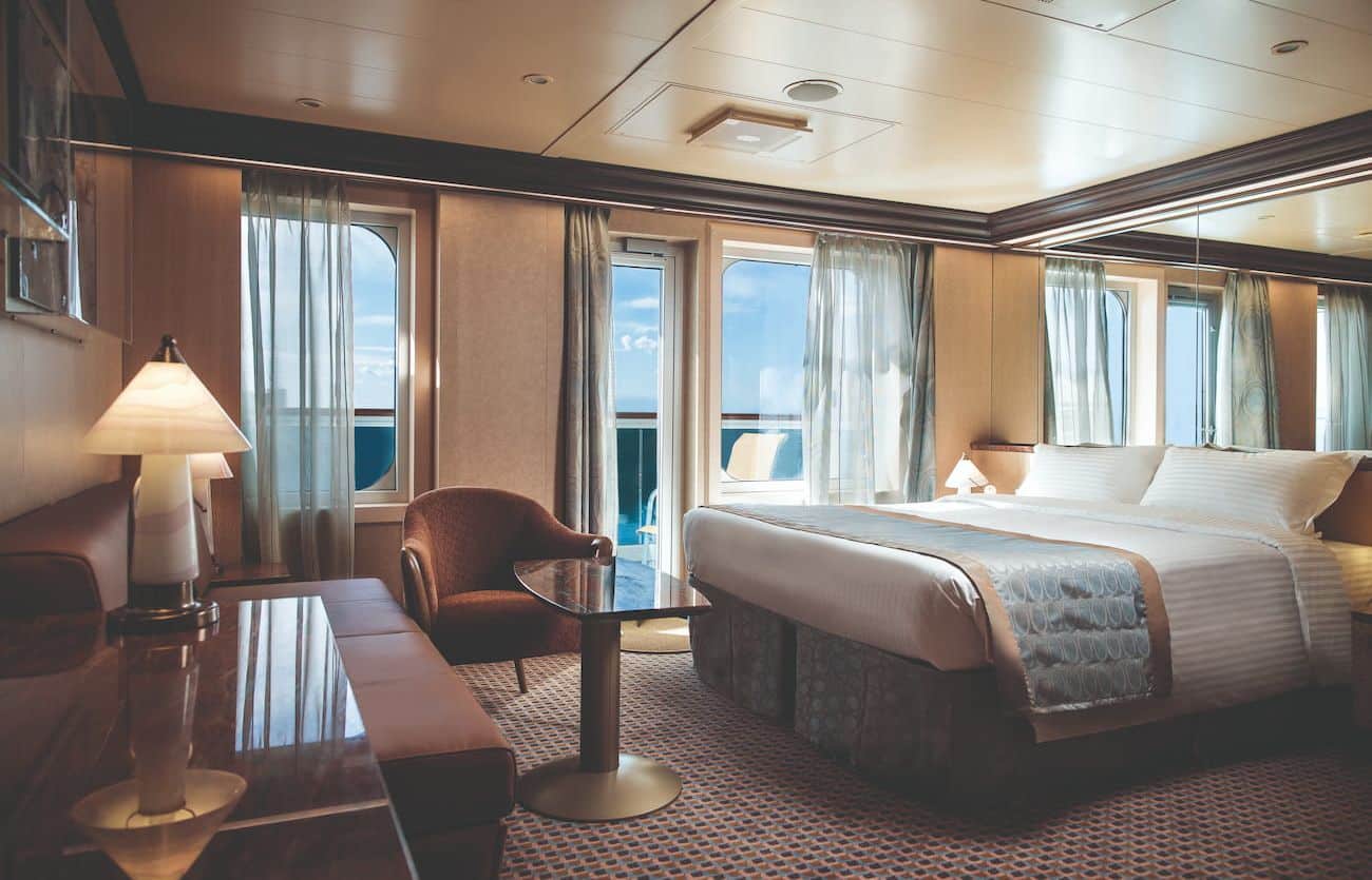 Costa Diadema balcony suite with floor-to-ceiling doors, seating area, and a large bed.