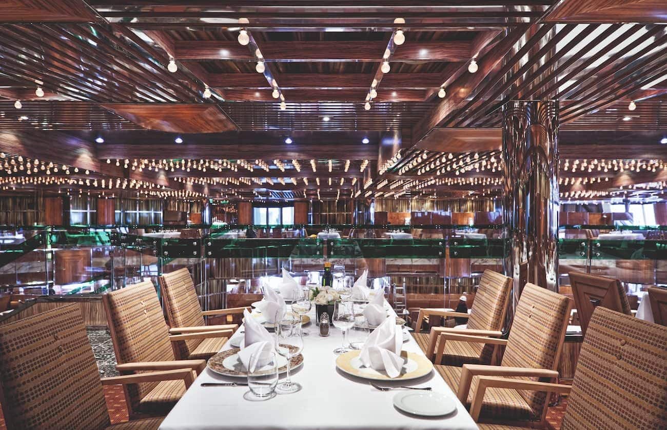 Gattopardo Restaurant on Costa Fascinosa with set tables, striped armchairs, mirrored walls, and warm wood ceilings.