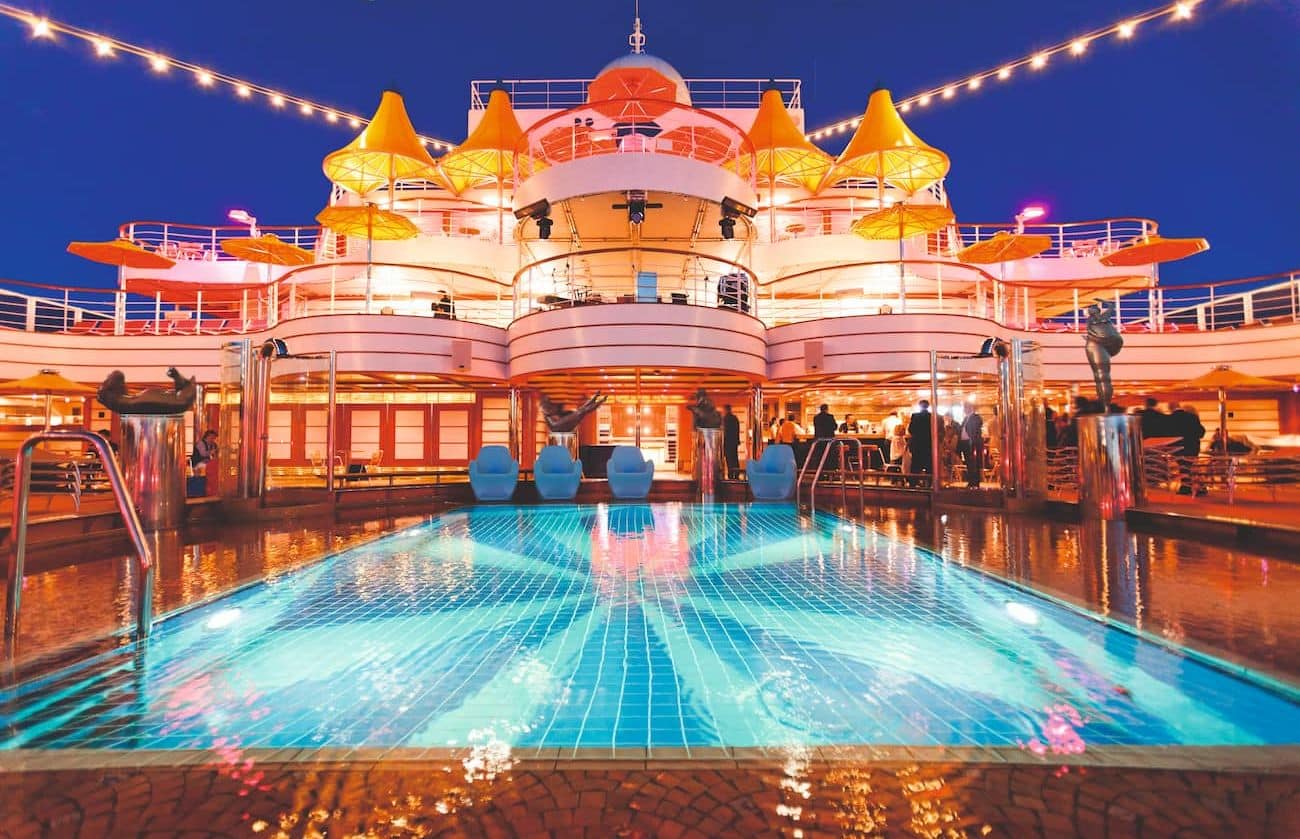 Costa Fascinosa Incantesimo Pool at Lido Via Col Vento glowing at dusk beneath yellow canopy structures.