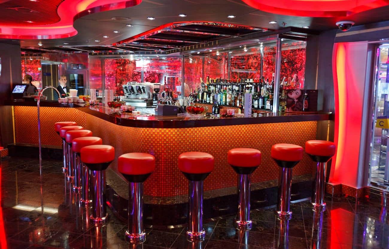 Red-lit piano bar with curved counter and stools