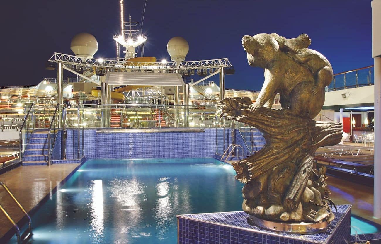 Costa Fortuna Lido Oceania pool deck at night with illuminated water and a sculptural fountain.