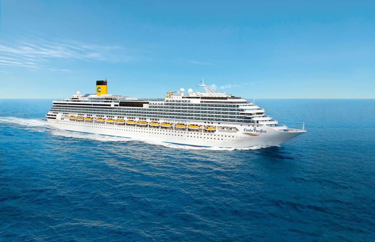 Costa Pacifica sailing across open blue water under a clear sky in a broad starboard-side view