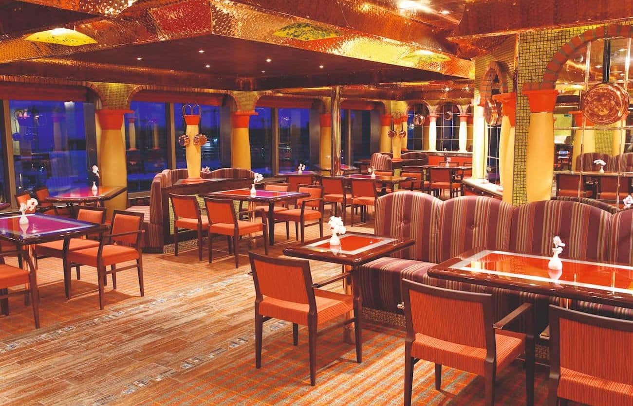 La Paloma Restaurant Buffet with striped seating, wood tables, golden columns, and wide windows overlooking the sea