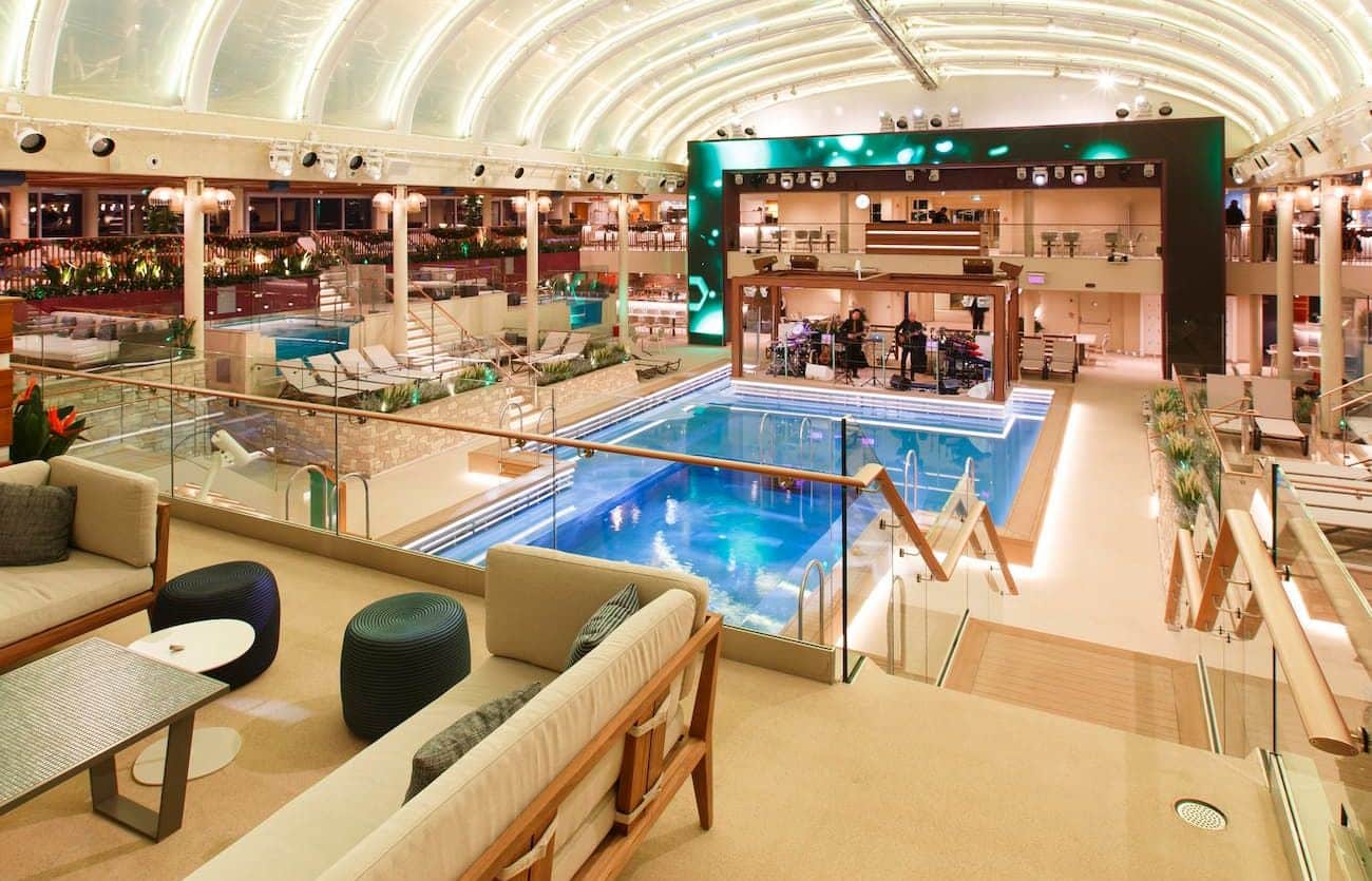 Beach Club pool area with lounge seating, glass railings, and a stage beneath the illuminated canopy.