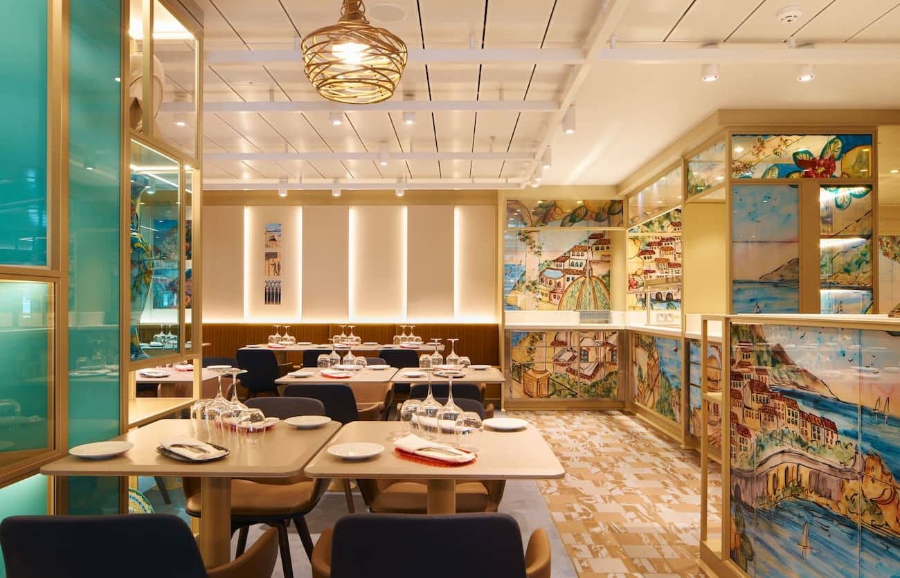 Le Anfore Restaurant dining room with illustrated wall panels, neatly set tables, and warm lighting in a bright contemporary interior.