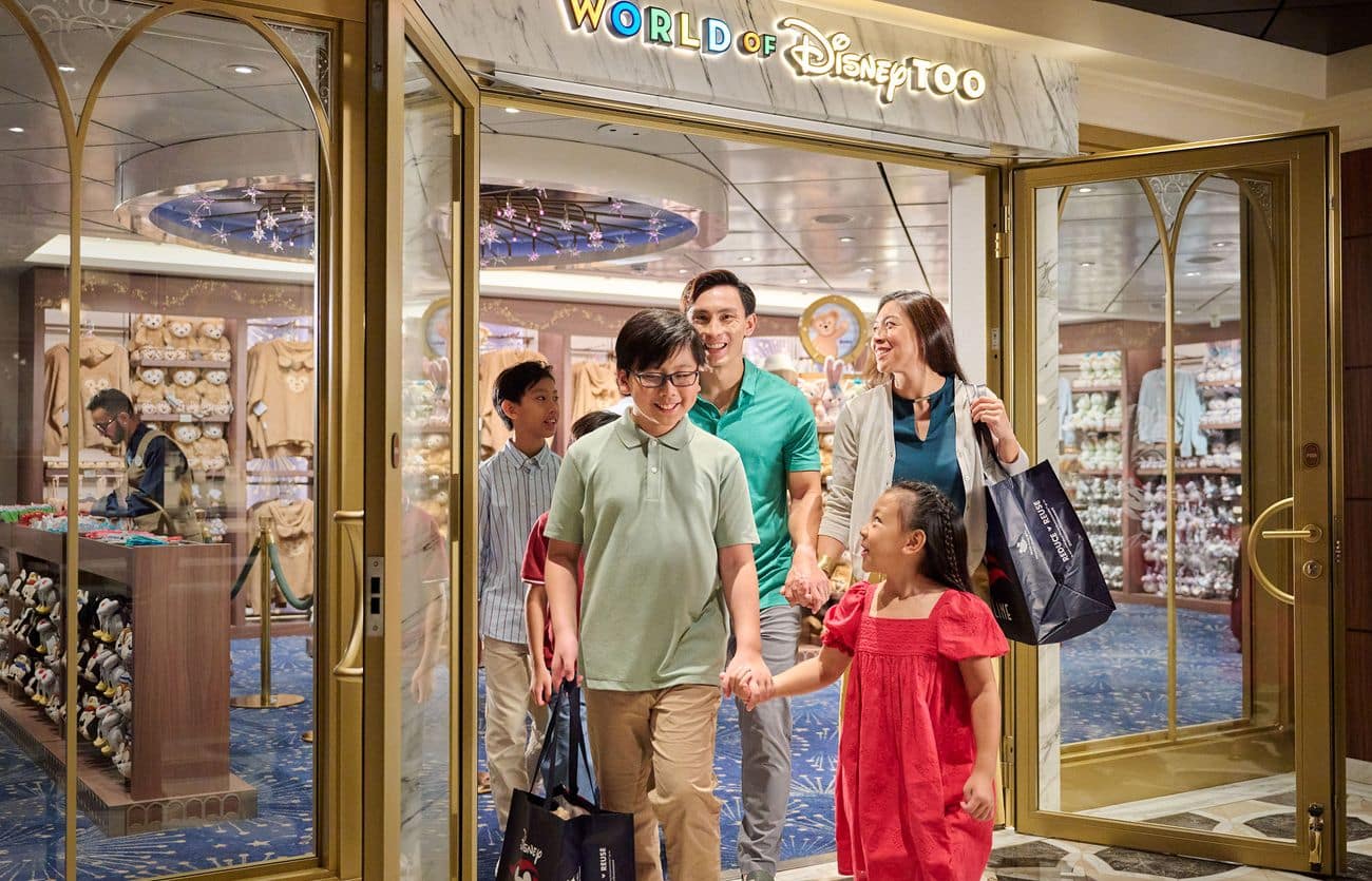 Family leaving World of Disney Too aboard Disney Adventure with shopping bags, while plush displays fill the store behind them