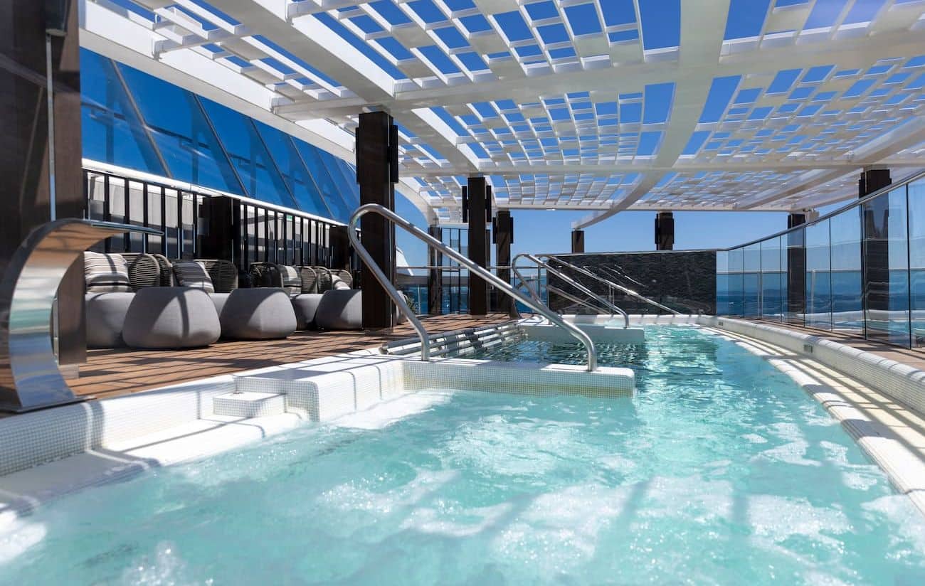 Aquamar Terrace pool deck with shaded loungers, glass railings, and sea views