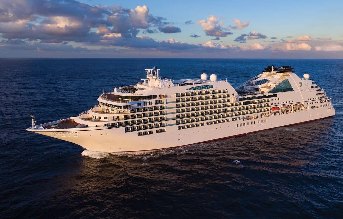 Seabourn Encore port side aerial view sailing at sea under a cloud-filled sky.
