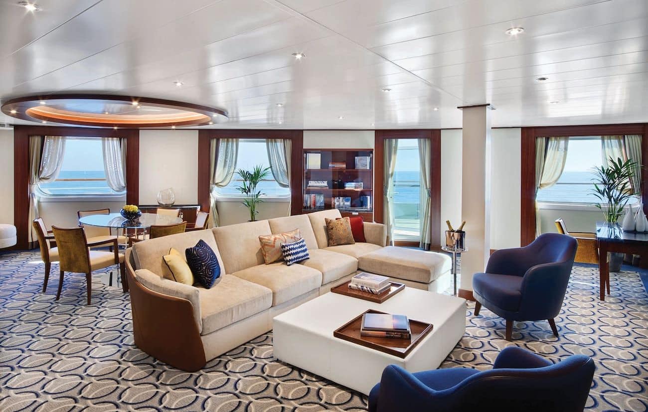 Signature Suite living room with veranda access, dining table, and sea views.