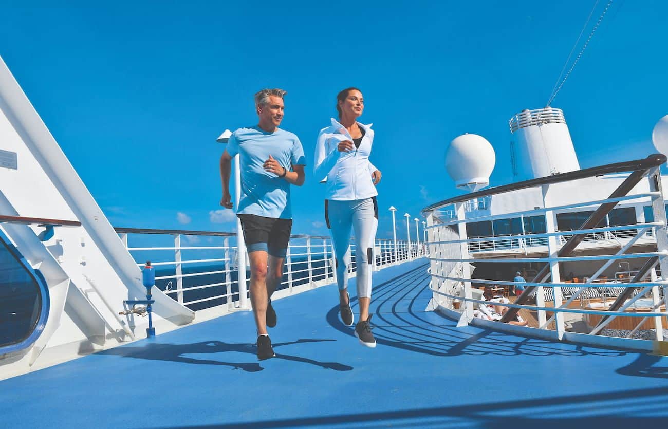 Guests jogging on the Fitness Track aboard a cruise ship under a clear blue sky