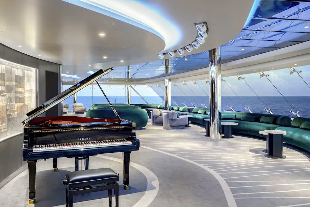 Grand piano and ocean-view seating inside the new MSC Yacht Club