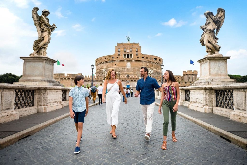 Family walking across Ponte Sant’Angelo toward Castel Sant’Angelo in Rome