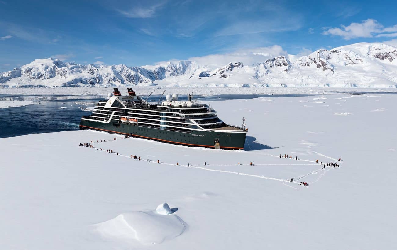 Seabourn Cruise Line guests walking on Antarctic sea ice beside Seabourn Pursuit