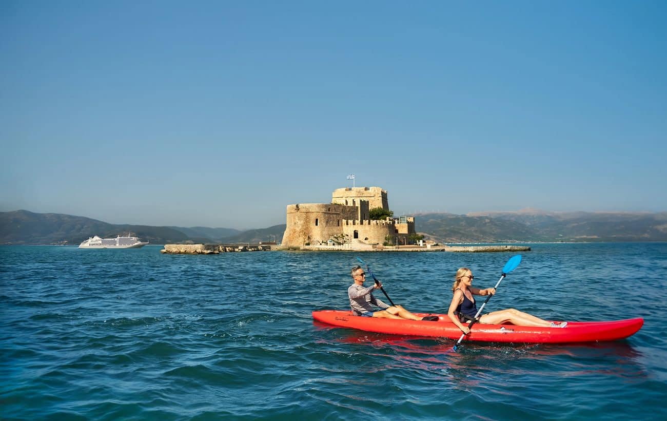 Guests kayaking near Bourtzi Castle in Nafplion with Silver Muse offshore