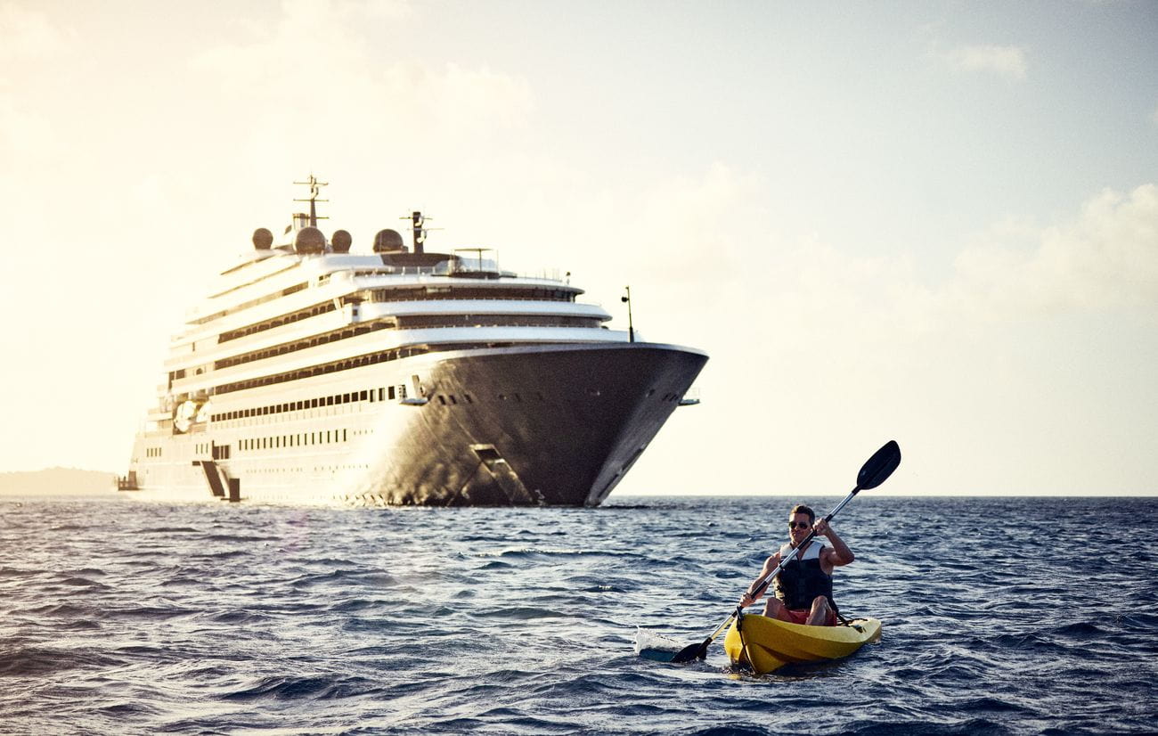 Kayaker paddling beside the luxury yacht Evrima at sea