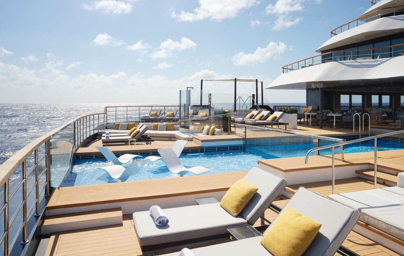 Evrima pool deck with loungers and infinity-style pools overlooking the sea