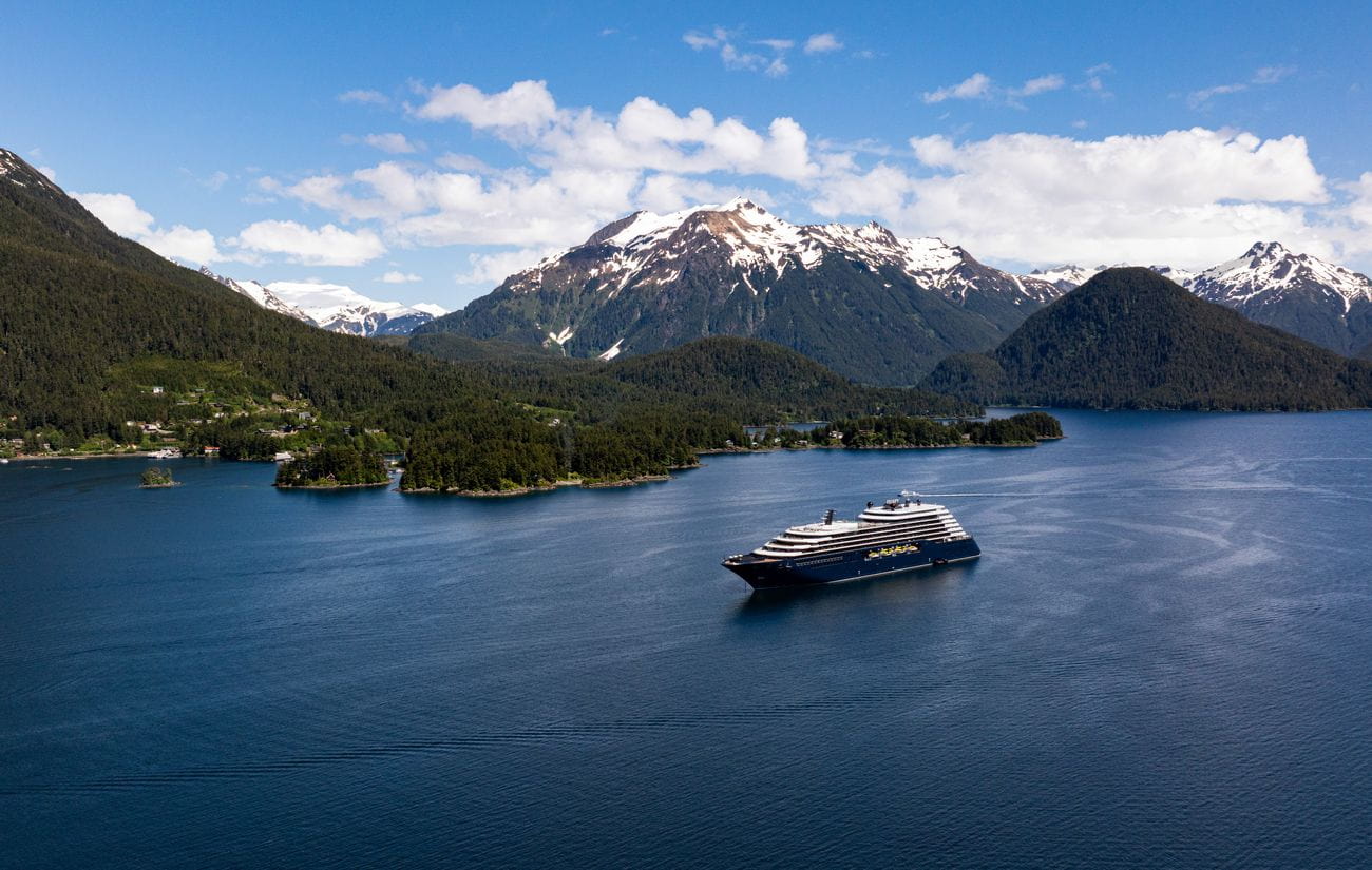 Luminara sailing through calm Alaskan waters beneath snow-capped mountains